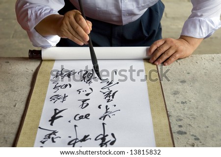A Chinese calligrapher at work writing on a scroll