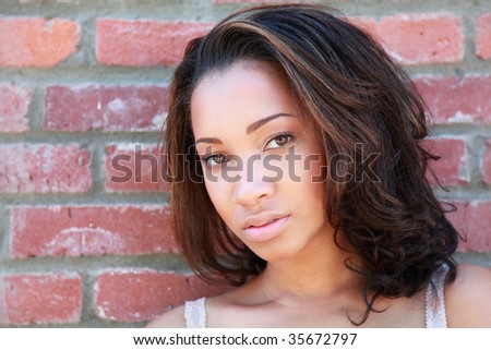 Portrait of a beautiful young lady in front of a red brick wall