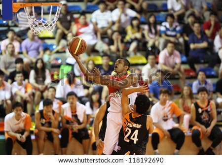 KUALA LUMPUR - OCTOBER 28: Dragons\' Satyaseelan (white) rolls in the ball to score against Firehorse team in a Malaysia National Basketball League match on October 28, 2012 in Kuala Lumpur, Malaysia.