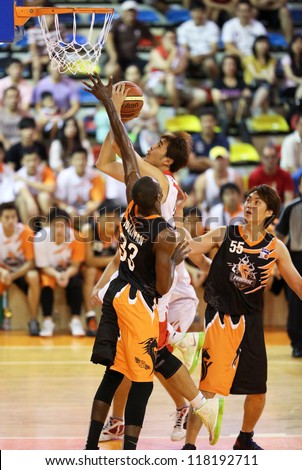 KUALA LUMPUR - OCTOBER 28: Dragons\' Chee Li Wei (white) scores against Firehorse\'s defense (black) in a Malaysia National Basketball League match on October 28, 2012 in Kuala Lumpur, Malaysia.