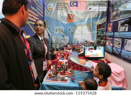 SUBANG JAYA - NOVEMBER 10: A Malaysian inventor explains to visitors how the Nanny robot works taking care of an infant at the World Robot Olympaid on November 10, 2012 in Subang Jaya, Malaysia.