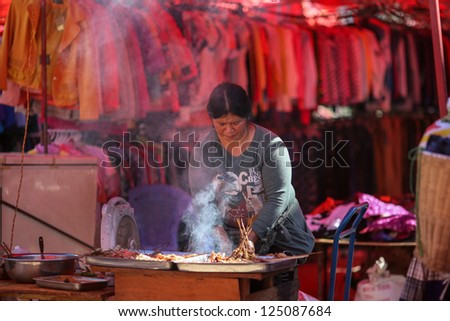 LAOMENG - DECEMBER 16: Food vendor prepares food for sale at a market in Lao Meng, China on December 16, 2012. People from 13 tribes/ethnic groups from China and Laos congregate here to trade daily.