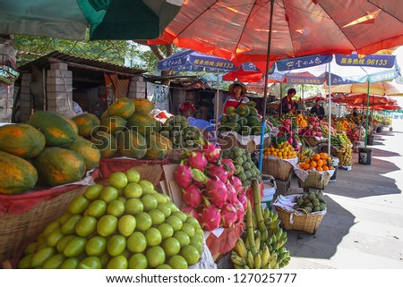 KUNMING - DECEMBER 20: Fruit sellers wait for customers in fruit stalls on a highway to KunMing city, China on December 20, 2013. A vibrant economy spawns private entrepreneurship and businesses.