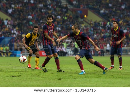 KUALA LUMPUR - AUGUST 10: FC Barcelona\'s Andres Iniesta (blue boots) dribbles the ball in a friendly match vs Malaysia at the Shah Alam Stadium on August 10, 2013 in Malaysia. Barcelona wins 3-1.