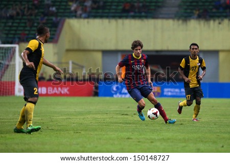 KUALA LUMPUR - AUGUST 10: FC Barcelona\'s Sergio Roberto (maroon/blue) dribbles the ball in a friendly match vs Malaysia at the Shah Alam Stadium on August 10, 2013 in Malaysia. Barcelona wins 3-1.