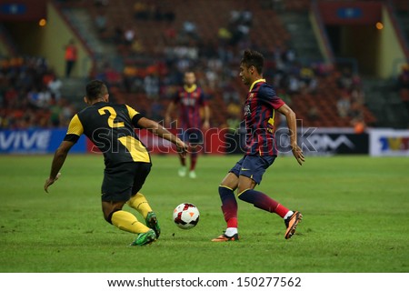 KUALA LUMPUR - AUGUST 10: FC Barcelona \'s Neymar (maroon/blue) dribbles past Malaysia\'s Mahalli (2) in game played at the Shah Alam Stadium on August 10, 2013 in Malaysia. FC Barcelona wins 3-1.