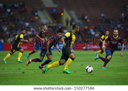 KUALA LUMPUR - AUGUST 10: Malaysia\'s Mahalli (2) controls the ball watched by Barcelona\'s Iniesta (right) in game played at the Shah Alam Stadium on August 10, 2013 in Malaysia. FC Barcelona wins 3-1.
