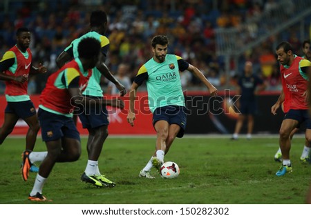 KUALA LUMPUR - AUGUST 9: FC Barcelona \'s Gerard Pique dribbles the ball during training at the Bukit Jalil National Stadium on August 09, 2013 in Malaysia. FC Barcelona is on an Asia Tour to Malaysia.