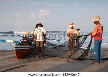 PADANG - AUGUST 25: Fishermen work as a team harvest the fish caught in the fishing nets in Padang, West Sumatera, Indonesia on August 25, 2013. Resources from the sea is a major revenue earner.