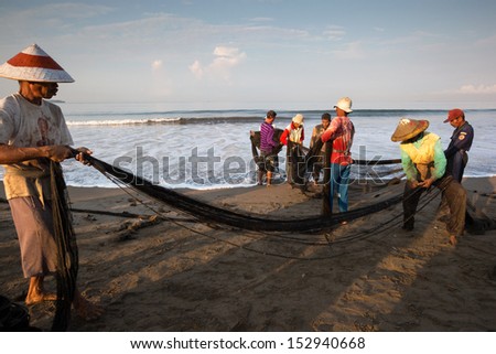 PADANG - AUGUST 25: Fishermen work as a team pull in the fishing nets from the sea in Padang, West Sumatera, Indonesia on August 25, 2013. Resources from the sea is a major revenue earner.