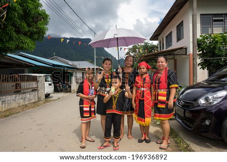 SARAWAK, MALAYSIA: JUNE 1, 2014: A family wearing traditional Bidayuh costumes wait for the parade to pass through their house, in a procession celebrating thanksgiving day, called the Gawai festival.
