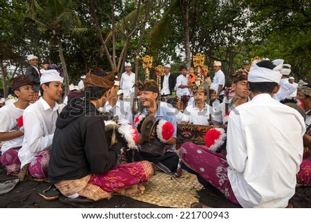 BALI, INDONESIA - SEPTEMBER 19, 2014: Traditional Balinese musical troupe plays music to accompany the prayer ceremonies for the Nyaben 12th day ceremony, to throw the cremated ashes into the sea.