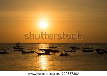 silhouettes of fishing boats at sunset in Bali.