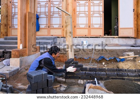 JEONJU, SOUTH KOREA - 03 NOVEMBER 2014: A traditional brick layer constructs a brick wall to extend the house. This traditional building method is still used in the rural parts of South Korea.