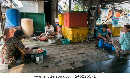 PULAU KETAM, MALAYSIA - JANUARY 18, 2015: Villagers work in a sea-food factory removing shells from prawns and shrimps. Pulau Ketam (Crab Island) is famous for sea food produce and restaurants.
