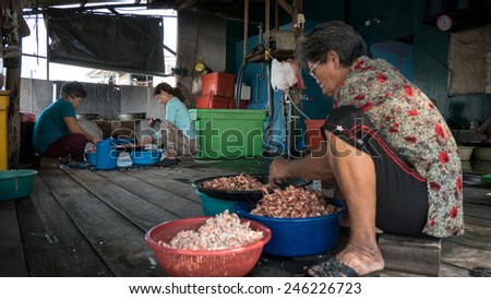 PULAU KETAM, MALAYSIA - JANUARY 18, 2015: Villagers work in a sea-food factory removing shells from prawns and shrimps. Pulau Ketam (Crab Island) is famous for sea food produce and restaurants.