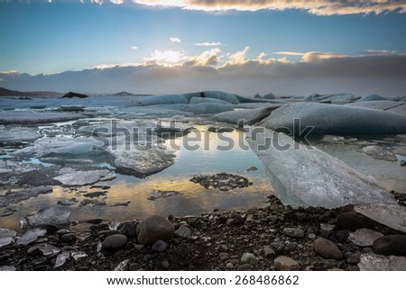 Glacier ice lagoon during sunset in Jokullsarlon, Iceland. The glacier breaks up into ice blocks in the lagoon before flowing out to sea as icebergs.