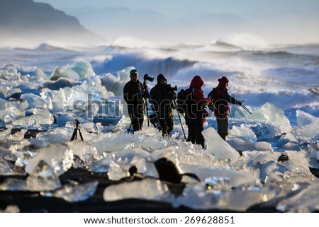ICELAND - MARCH 26, 2015: Photographers views the sunrise amidst the blocks of ice from the glaciers that break up and washed ashore by the strong waves of the North Atlantic sea in Iceland.