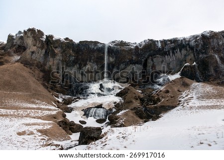 View of mountains, waterfalls, snow covered land and river in the countryside in southern Iceland.