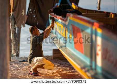 SABAH, MALAYSIA - JUNE 28, 2008: An unidentified boat maker makes the final touches to a fishing boat he had made in his factory. Boats are a major form  of transportation on this island.