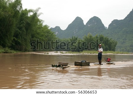 XINGPING, CHINA - MAY 19: A local farmer travels up and down river in a traditional raft on the Li Jiang River. May 19, 2010 in Xing Ping, China.