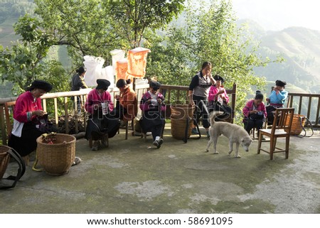 GUILIN, CHINA - MAY 23: Farm womenfolk work on clothes embroidery in front of their home in Longji on May 23, 2010. The traditional costumes and lifestyle make Lingji a popular tourist destination.