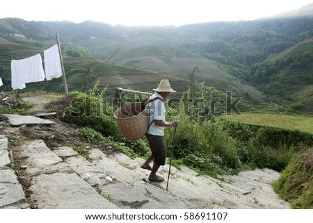 GUILIN, CHINA - MAY 23: A farmer goes down the hill slope to work at his farm in Longji on May 23, 2010. The scenic Longji terraced rice fields is a popular tourist destination.