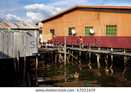 LABUAN,MALAYSIA-JULY 16: A village boy walks along the wooden walkways linking the homes of this floating water village, July 16, 2010 in Labuan, Borneo. Patau-Patau village sits off the shores of Labuan.