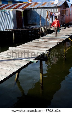 LABUAN,MALAYSIA-JULY 16: A village boy walks along the wooden walkways linking the homes of this floating water village, July 16, 2010 in Labuan, Borneo. Patau-Patau village sits off the shores of Labuan.