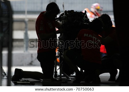 SEPANG, MALAYSIA - FEBRUARY 2: Aspar Team mechanics work on Hector Barbera\'s motorbike during the 2011 MotoGP winter tests at the Sepang International Circuit. February 2, 2011 in Malaysia