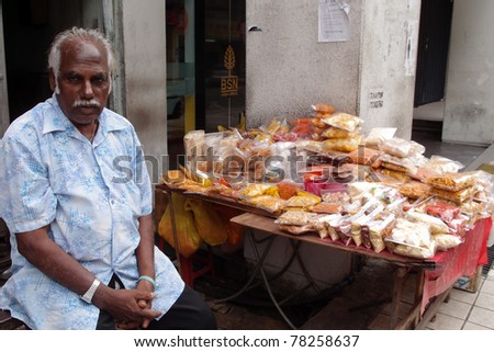 KUALA LUMPUR - MAY 22: An Indian trader sells snack food on May 22, 2011 in Kuala Lumpur, Malaysia. The snack food includes roasted peanuts, beans and a deep fried spiced flour strips known as muruku.
