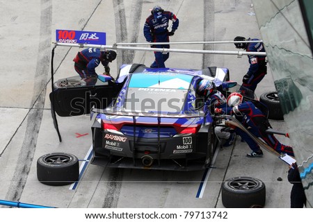 SEPANG, MALAYSIA - JUNE 19: Team Kunimitsu's pit-crew works on the car during pit-stop at the Sepang International Circuit before the Japan SUPER GT Round 3 race on June 19, 2011 in Sepang, Malaysia.