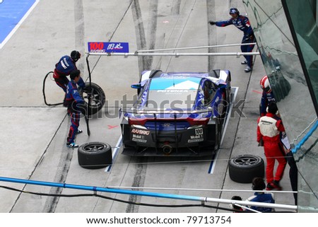 SEPANG, MALAYSIA - JUNE 19: Team Kunimitsu's pit-crew works on the car during pit-stop at the Sepang International Circuit before the Japan SUPER GT Round 3 race on June 19, 2011 in Sepang, Malaysia.