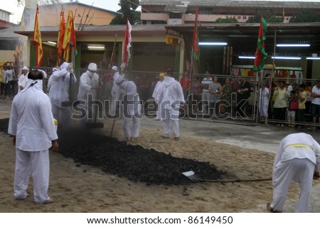 AMPANG, MALAYSIA – OCT 05: Devotees pound the charcoal in preparation for the fire-walk pit at the Lam Thian Kiong Temple during the annual ‘Nine Emperor Gods’ Festival on October 05, 2011 in Ampang, Malaysia.