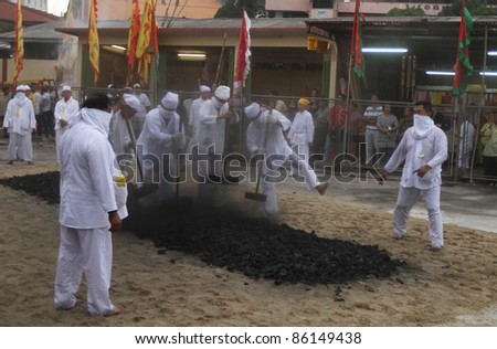 AMPANG, MALAYSIA – OCT 05: Devotees pound the charcoal in preparation for the fire-walk pit at the Lam Thian Kiong Temple during the annual ‘Nine Emperor Gods’ Festival on October 05, 2011 in Ampang, Malaysia.