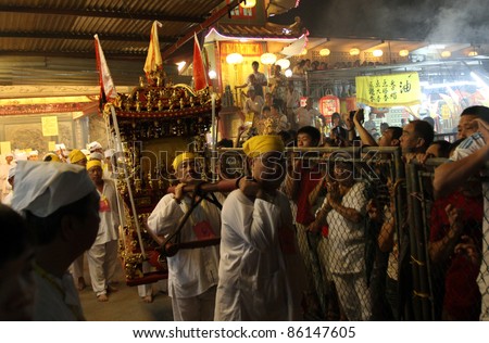 AMPANG, MALAYSIA – OCT 05: Taoist devotees carry religious items for the fire-walk ceremony at the Lam Thian Kiong Temple during the annual ‘Nine Emperor Gods’ Festival on October 05, 2011 in Ampang, Malaysia.