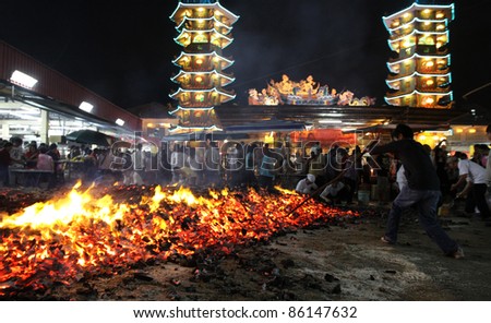 AMPANG, MALAYSIA – OCT 05: A devotee prods the fire pit to collect charcoal blessed after the fire-walk at the Lam Thian Kiong Temple during the ‘9 Emperor Gods’ Festival on October 05 2011 in Ampang, Malaysia.