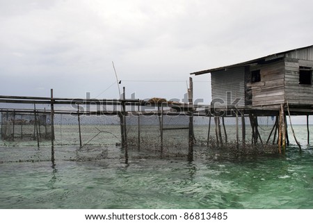 A sea gypsy home on stilts in the sea off the coast of Semporna on Borneo Island. The nets trap fish from the sea. The sea-gypsies had been seafarers and fishermen for generations.