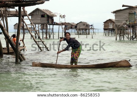 SABAH, MALAYSIA - SEPT 10: A sea gypsy returns home by boat in Bodgaya Island on September 10, 2011 in Sabah, Malaysia. Sea gypsies live in houses built on stilts planted on the shallow coral seas.