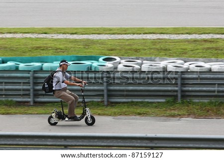 SEPANG, MALAYSIA - OCTOBER 21: A journalist on a small bike besides the track to cover the free practice session at the Shell Advance Malaysian GP 2011 on October 21, 2011 at Sepang, Malaysia.