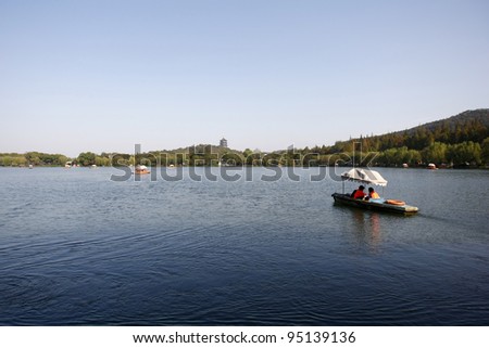 HANGZHOU, CHINA - NOVEMBER 26: Visitors on a paddle boat tour the West Lake, a UNESCO World Heritage site, viewing the hills beyond on November 26, 2011 in Hangzhou, China.