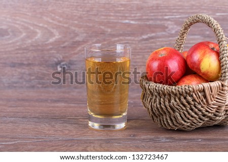 apples in a basket with apple juice on a wooden background