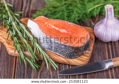 Fresh raw salmon fish steaks with fresh herbs on wooden background