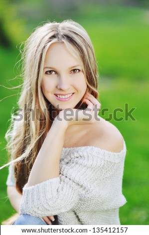 Young woman outdoors portrait with beautiful long hair smiles