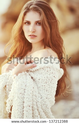 Young beautiful fashion model with hair and make-up professionally done outdoors back lit at sunset