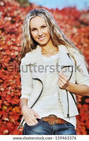 autumn portrait of the young beautiful woman in a white sweater and a vest