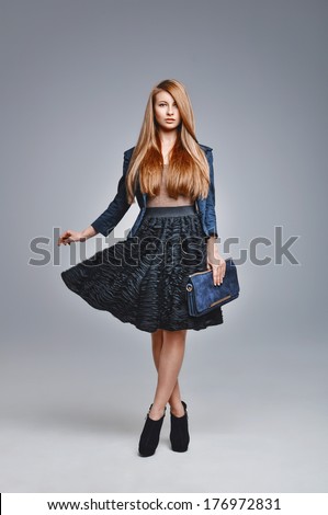 The glamourous sexy woman poses in a business suit. Stylish accessories, bag, high heels. Fashionable clothes.