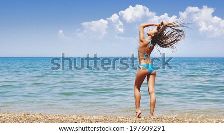 Jumping happy girl on the beach, fit sporty healthy sexy body in bikini, woman enjoys wind, freedom, vacation, summertime fun concept