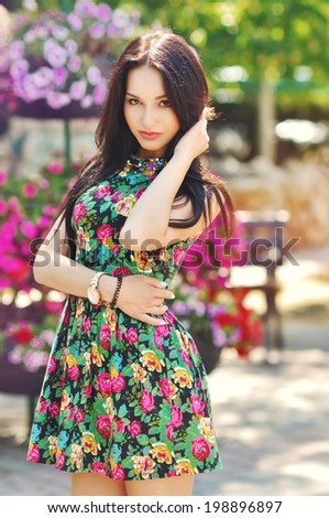 the fashionable beautiful girl walks around the city in a summer dress among flowers in the summer