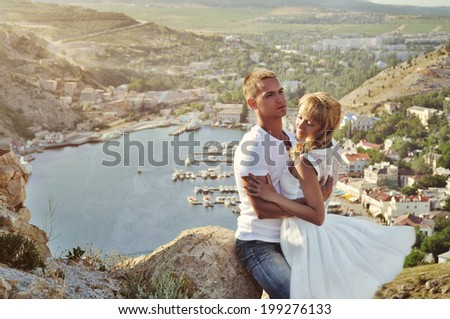 Stunning sensual outdoor portrait of young stylish fashion couple kissing in summer.  Soft sunny colors.